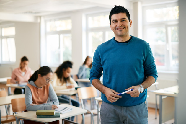 Porträt eines Lehrers während einer Klasse an der High School, der in die Kamera schaut.