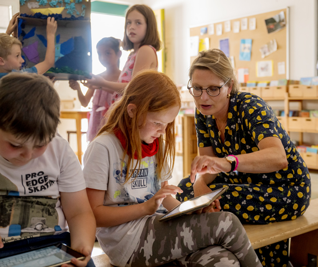 Ministerin Stefanie Hubig mit einem Mädchen schauen auf einem iPad