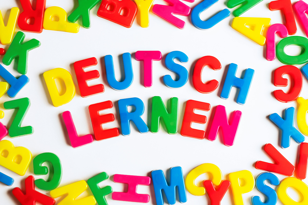 auf einem Tisch verteilte Buchstaben, im Zentrum bilden sie den Spruch: Deutsch lernen