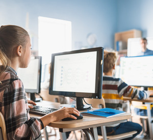 Mehrere Schülerinnen und Schüler die jeweils einzeln vor einem Desktop-PC sitzen und arbeiten.