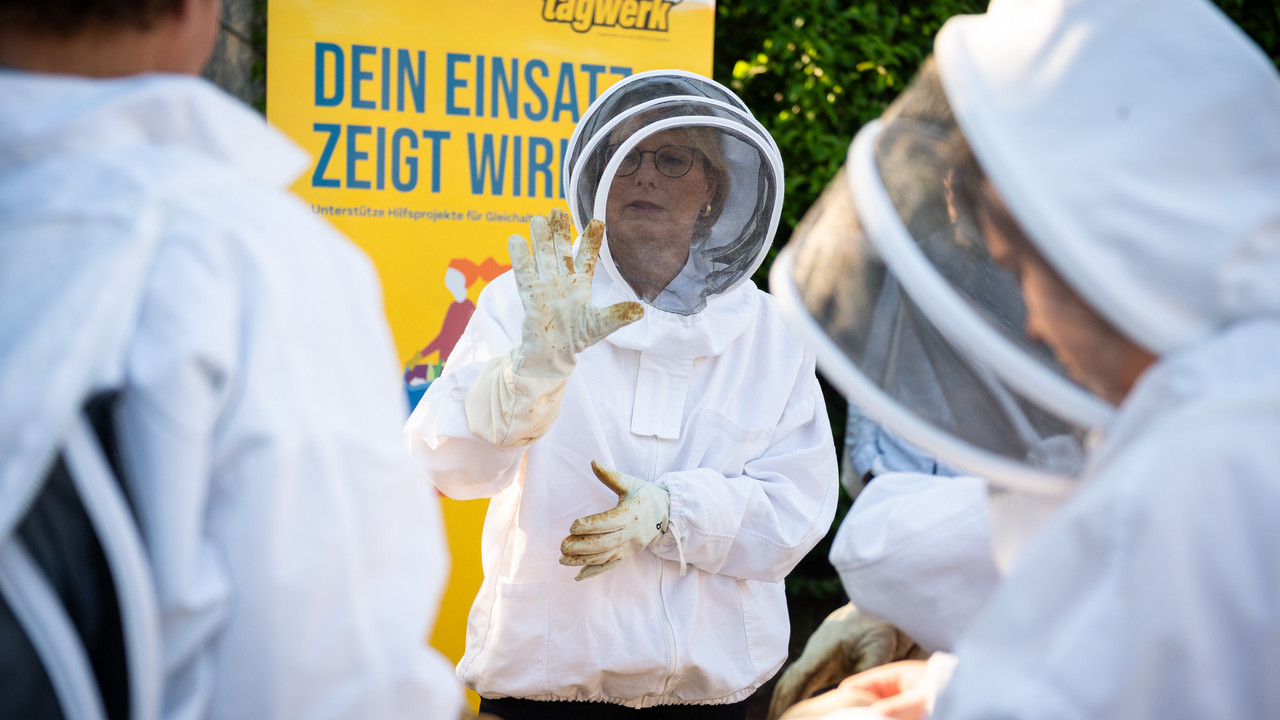 Auf dem Foto sieht man Bildungsministerin Hubig mit einem Bienenschutzanzug. 