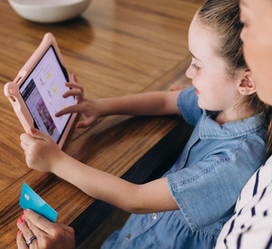 Eine Mutter schaut, welche Medien ihr Kind auf dem Tablet nutzt. 