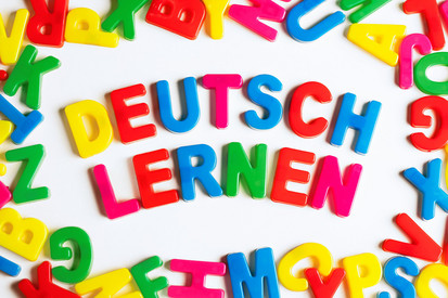 auf einem Tisch verteilte Buchstaben, im Zentrum bilden sie den Spruch: Deutsch lernen