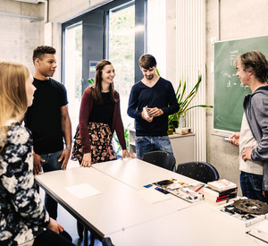 Lehrer vor einer Tafel im Gespräch mit Schülern aus der Oberstufe