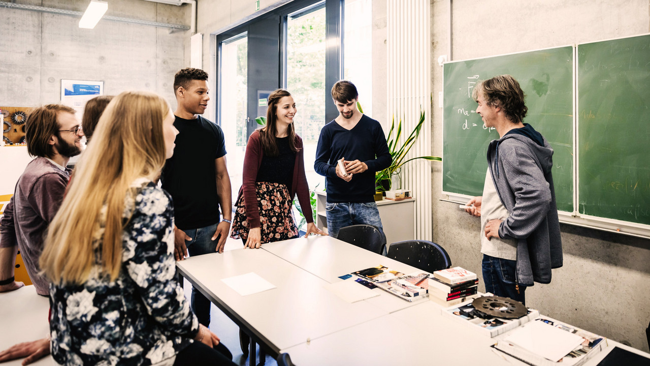 Lehrer vor einer Tafel im Gespräch mit Schülern aus der Oberstufe