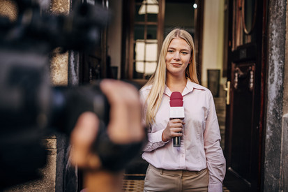 Frau mit Mikrofon vor einer Kamera