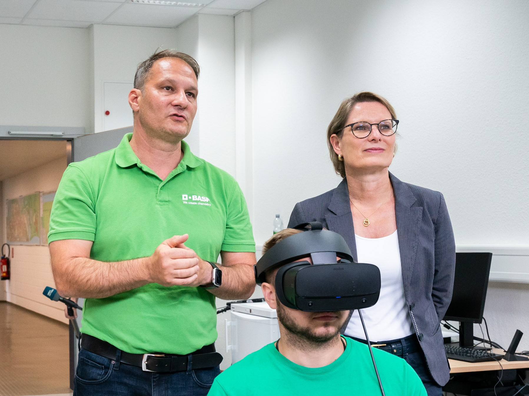 Auf dem Foto schaut jemand im Vordergrund durch eine VR-Brille. Im Hintergrund steht Ministerin Hubig mit einer weiteren Person. 