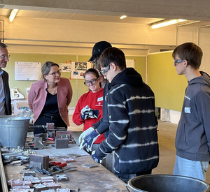 Auf dem Foto sehen Sie Bildungsministerin Dr. Stefanie Hubig. Sie schaut sich die Arbeit von Praktikantinnen und Praktikanten bei Römheld & Moelle an. 