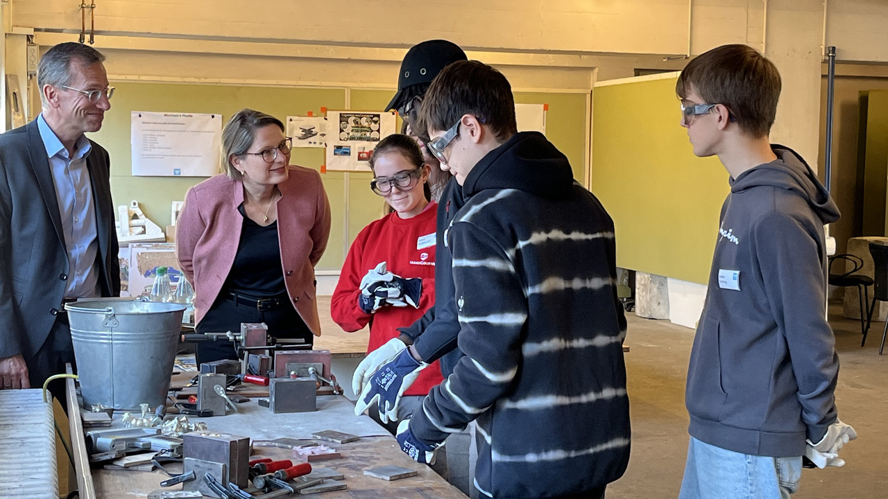 Auf dem Foto sehen Sie Bildungsministerin Dr. Stefanie Hubig. Sie schaut sich die Arbeit von Praktikantinnen und Praktikanten bei Römheld & Moelle an. 