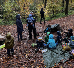 Auf dem Foto sieht man Erzieherinnen und Erzieher mit Kindern im Wald.