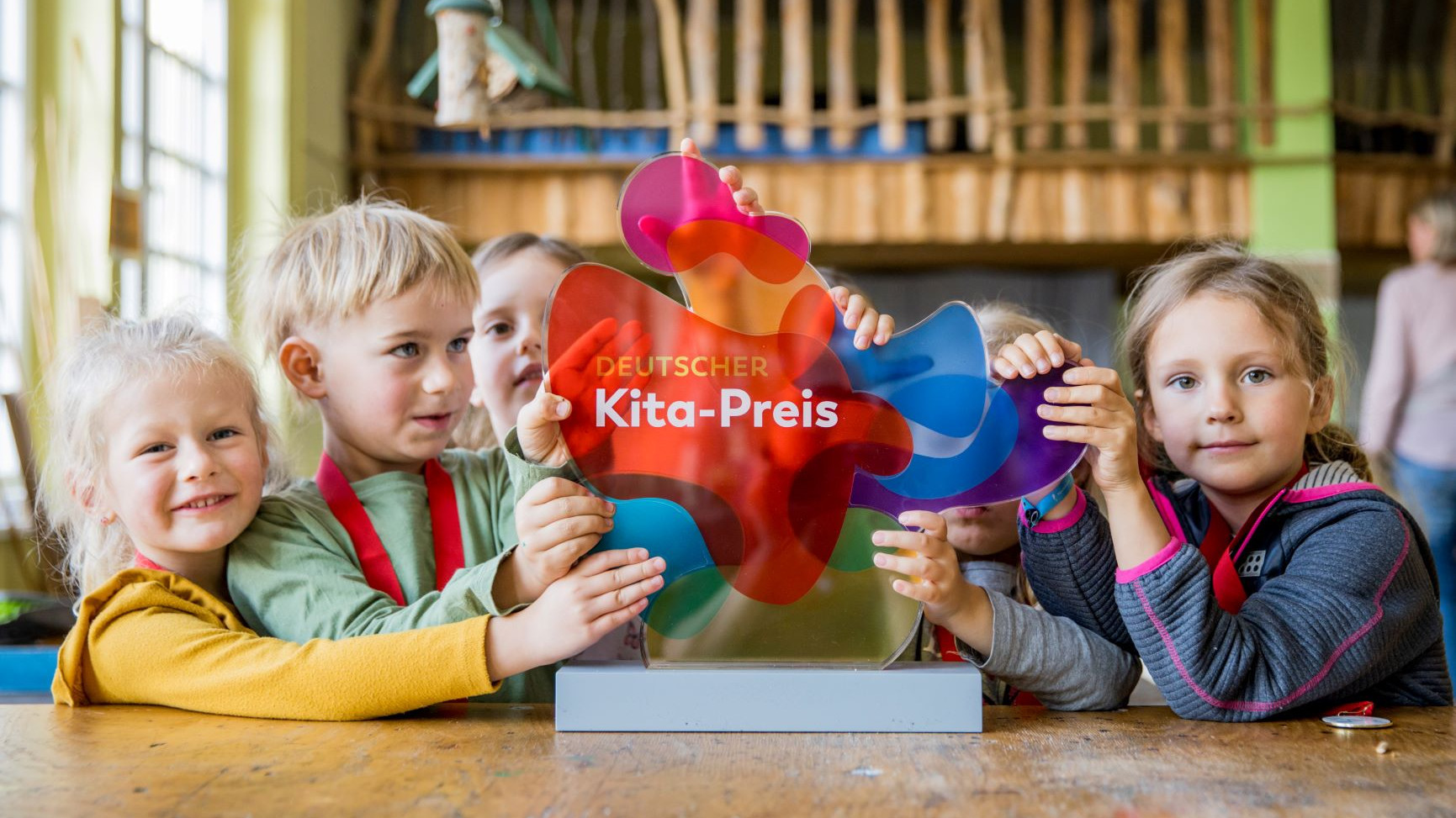 Kinder halten den deutschen Kitapreis in die Kamera.