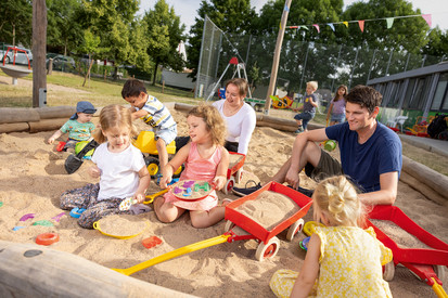 Kinder mit Eltern im Sandkasten