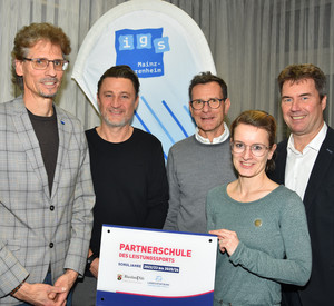 Das Foto bildet die offizielle Übergabe des begehrten Schildes ab. Von links nach rechts sind auf dem Foto zu sehen: Roland Wollowski (Schulleiter IGS Bretzenheim), Stefan Klören (Sportzweigleiter IGS Bretzenheim), Michael Stäudt (Mitarbeiter Schulsportreferat im Ministerium für Bildung RLP), Melanie Heß (LSB-Referentin für Leistungssport), Volker Weiß (Schulsportreferent im Ministerium für Bildung RLP)