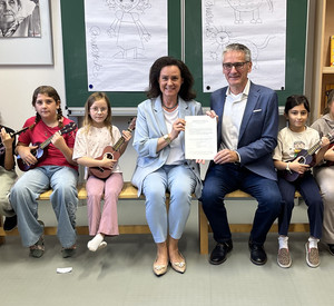Eingerahmt von den Kindern der Ukulele-Klasse an der Grundschule an der Burg Klopp in Bingen präsentieren Bildungsministerin Dr. Ute Eiling-Hütig und Volkshochschulverbandsvorsitzender Hendrik Hering die neue Rahmenvereinbarung.