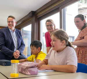 Ministerpräsident Alexander Schweitzer und Bildungsministerin Hubig mit einem Schülerin und einem Schüler sowie der betreuenden Lehrkraft der VHS des Feriensprachkurses.